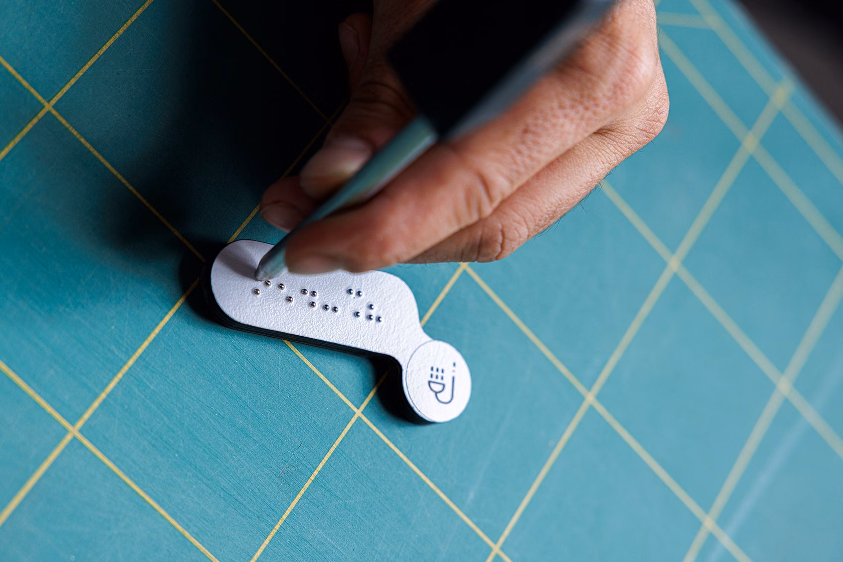 Detalhe de produção de placa em HPL com braille para sinalética inclusiva.
