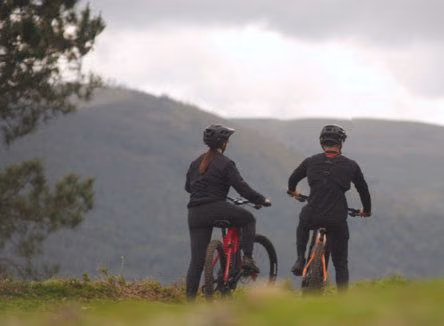 Dois ciclistas de BTT a olhar para a serra, em espaço natural.