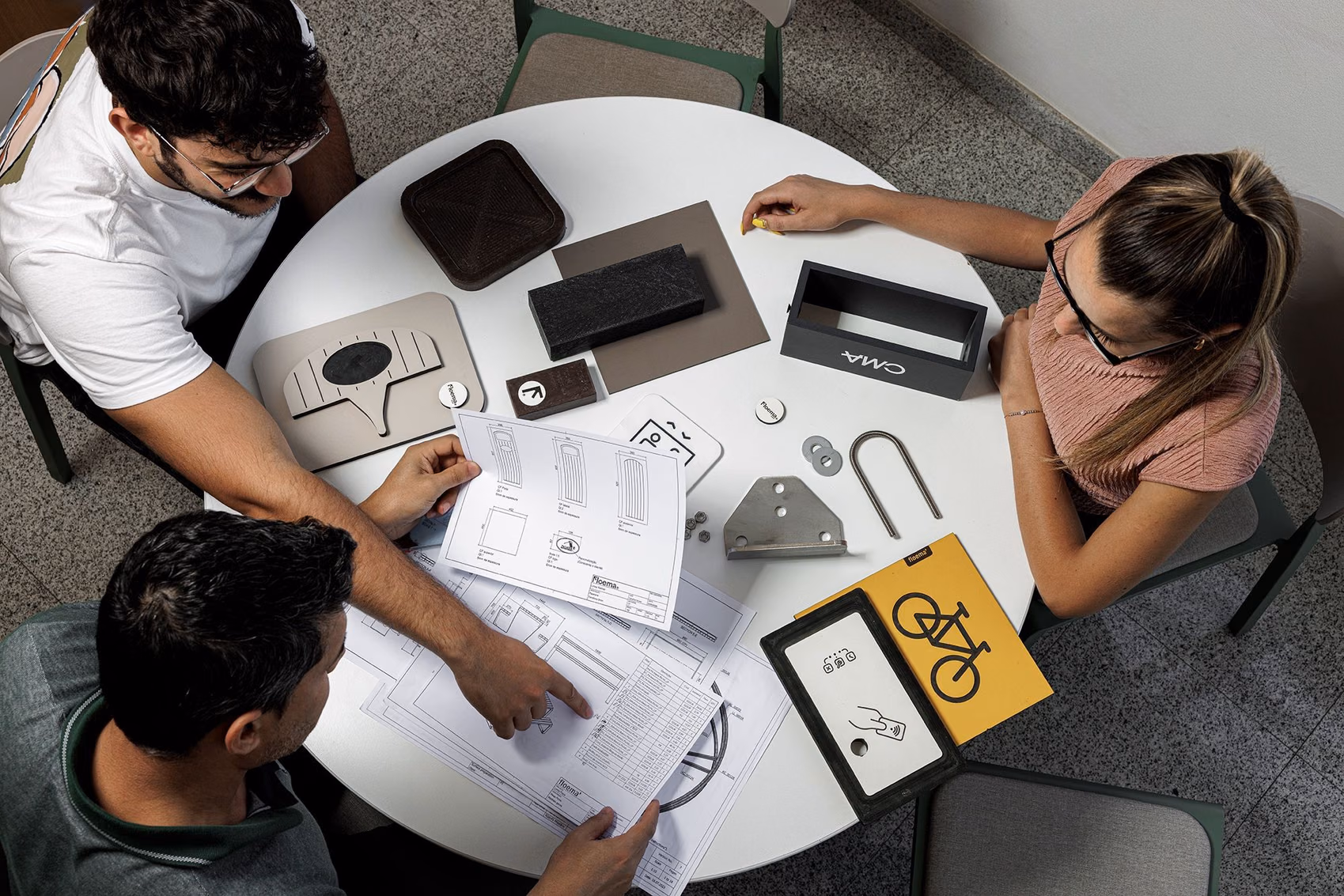 Equipa de design de produto da Floema em reunião de desenvolvimento para a Floema Urban e Floema Golf, com mesa com matérias primas como o HPL+ e plástico reciclado.