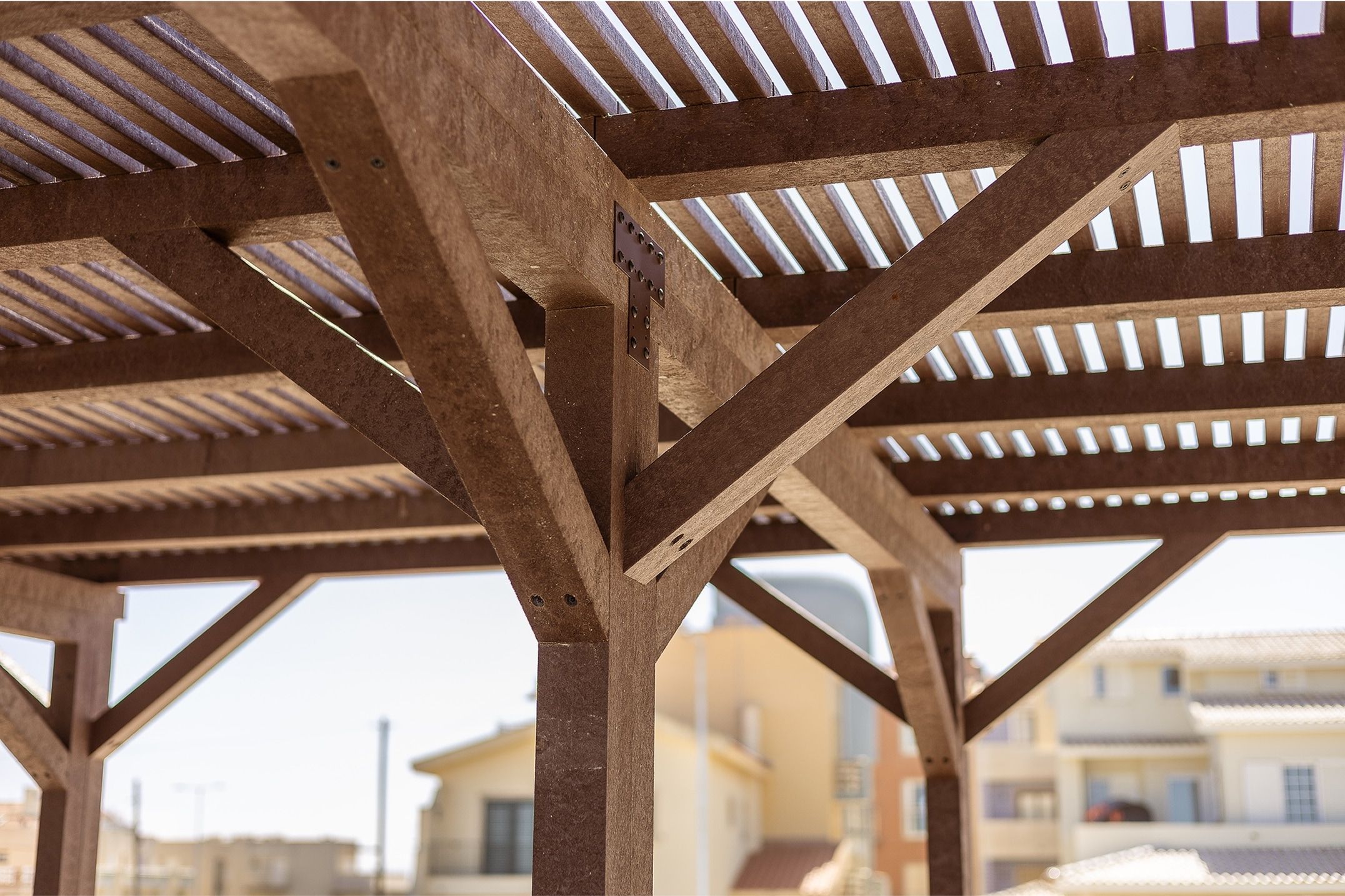 Detalhe de construção de pérgula em plástico reciclado castanho com design Floema
